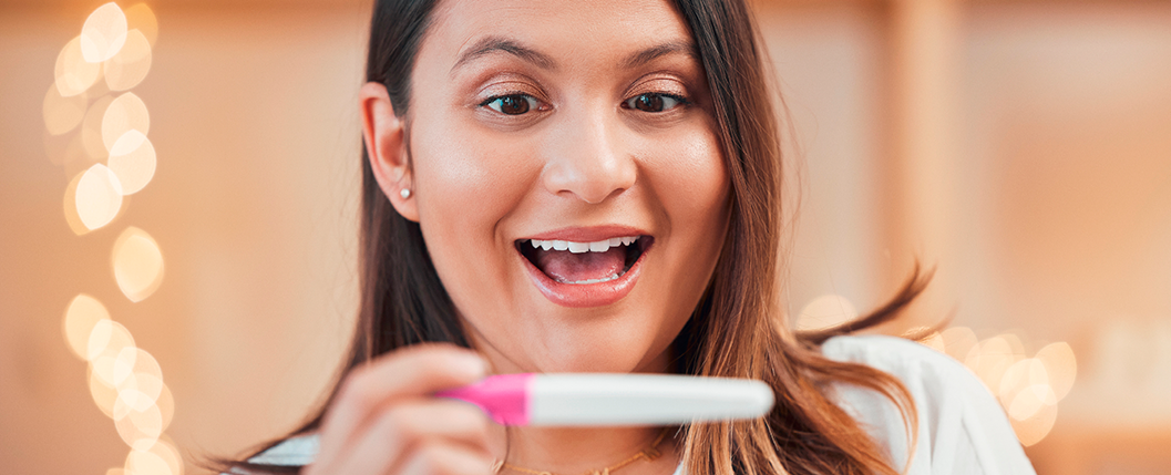 mulher sorrindo olhando teste de gravidez